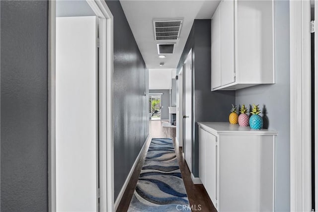 hall featuring baseboards, visible vents, and dark wood finished floors