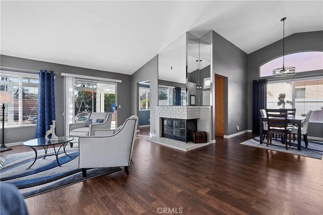 living area featuring a healthy amount of sunlight, a fireplace, baseboards, and wood finished floors