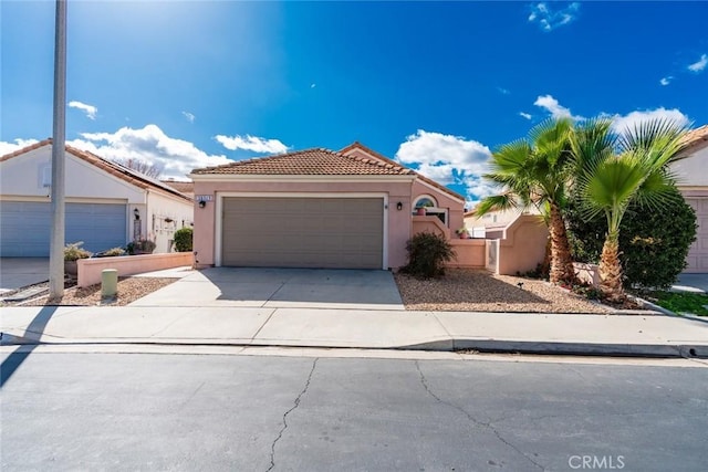 mediterranean / spanish home featuring a garage, a tile roof, concrete driveway, and stucco siding