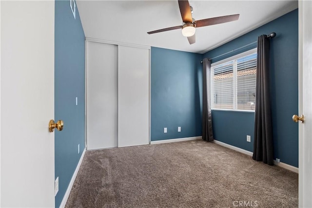 unfurnished bedroom with a ceiling fan, a closet, baseboards, and carpet flooring