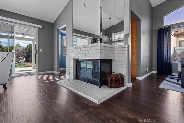 living area featuring a brick fireplace, plenty of natural light, baseboards, and wood finished floors