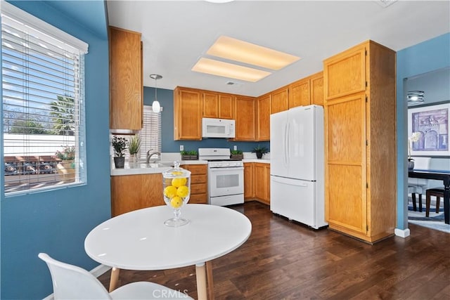 kitchen with brown cabinetry, white appliances, light countertops, and dark wood finished floors