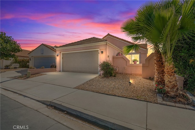 view of front of home featuring a garage, concrete driveway, a tiled roof, and stucco siding