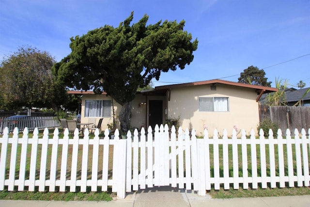 view of front of property with a fenced front yard, a front yard, and stucco siding