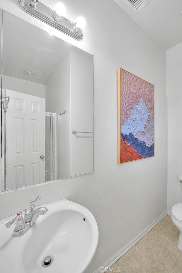 bathroom with toilet, a sink, visible vents, baseboards, and a stall shower