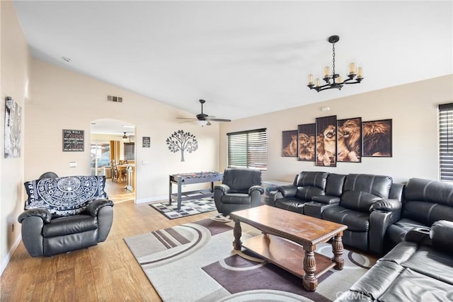 living room with lofted ceiling, ceiling fan with notable chandelier, and light wood-type flooring