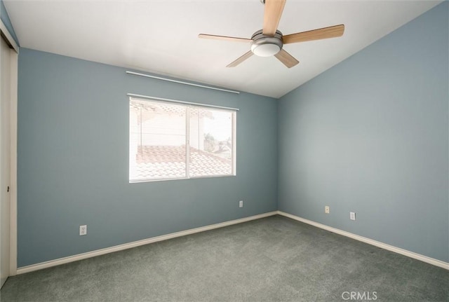 spare room featuring baseboards, vaulted ceiling, dark carpet, and ceiling fan