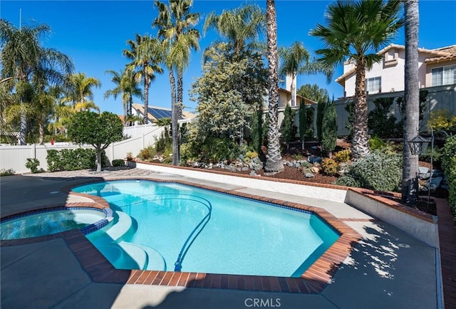 view of swimming pool with a fenced backyard and a pool with connected hot tub