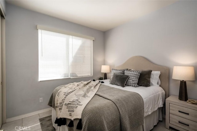 bedroom with multiple windows, light tile patterned flooring, and baseboards