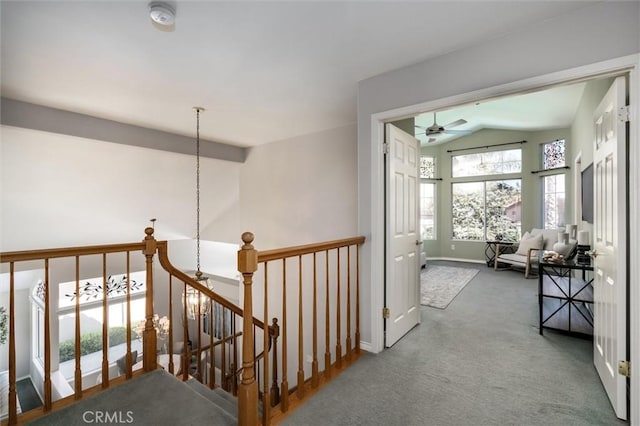 hallway featuring carpet, baseboards, lofted ceiling, and an upstairs landing