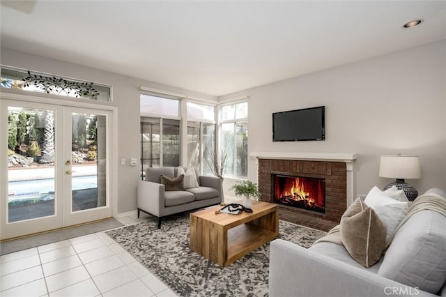 living room with french doors, light tile patterned flooring, and a brick fireplace