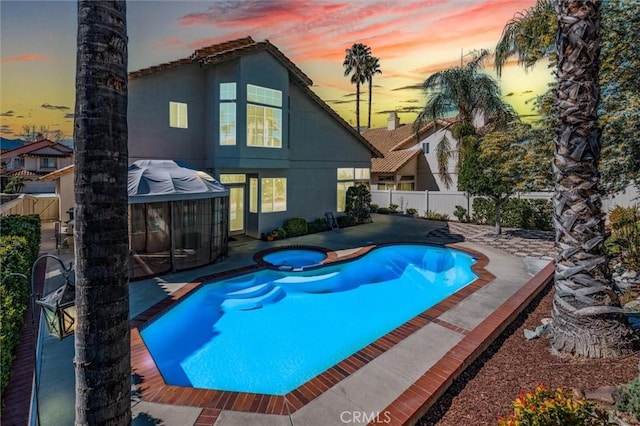 view of swimming pool featuring a patio area, a pool with connected hot tub, and fence