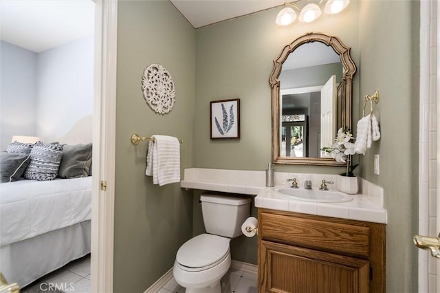 ensuite bathroom featuring ensuite bathroom, tile patterned flooring, toilet, vanity, and baseboards