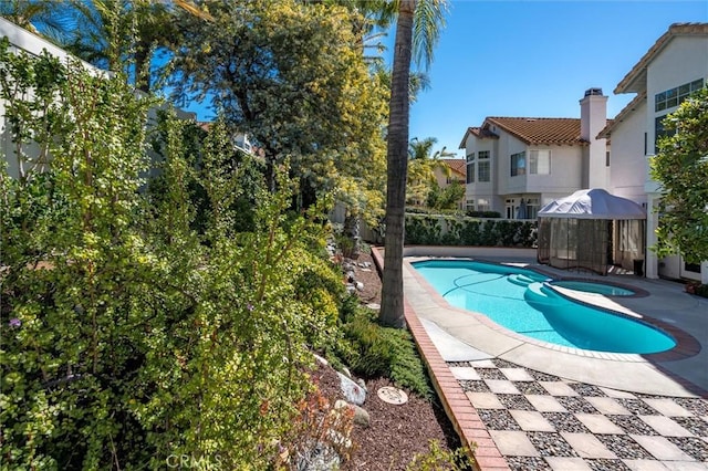 view of pool with a patio, fence, and a pool with connected hot tub