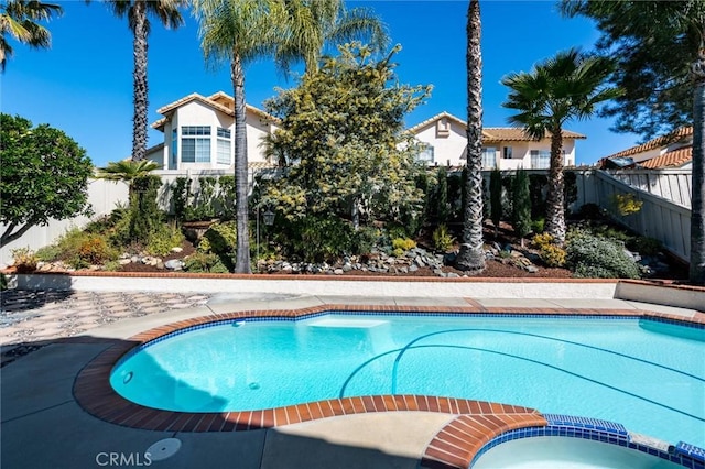 view of swimming pool featuring a fenced backyard and a pool with connected hot tub