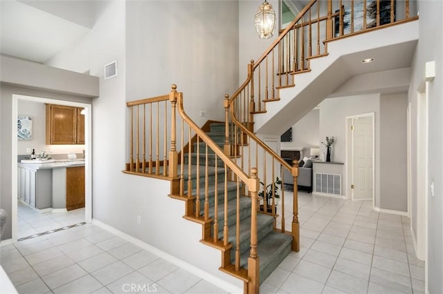 stairs with baseboards, a high ceiling, and visible vents