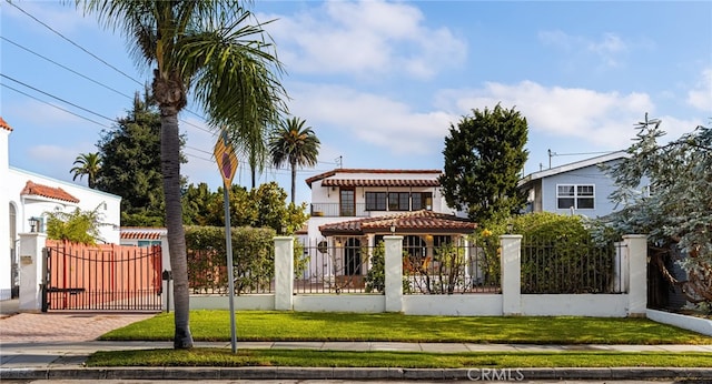 view of front of property featuring a fenced front yard, a gate, a tiled roof, and a front yard