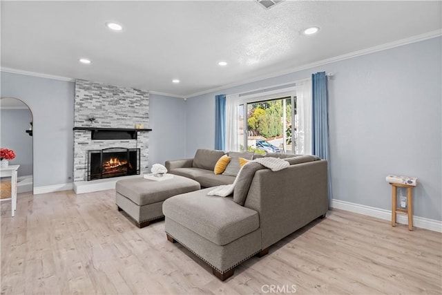 living room featuring light wood-type flooring, crown molding, and a fireplace