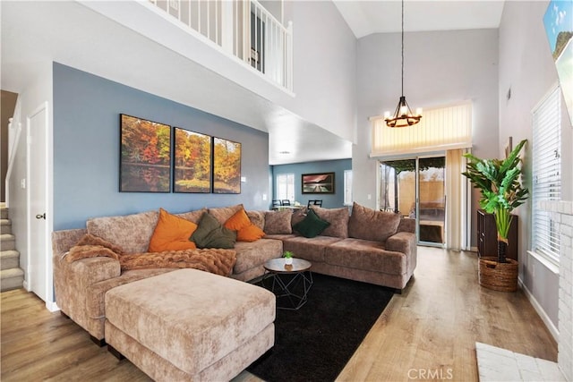 living room with a wealth of natural light, a chandelier, a high ceiling, and light wood-type flooring