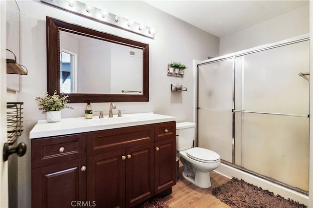 bathroom featuring an enclosed shower, hardwood / wood-style floors, vanity, and toilet