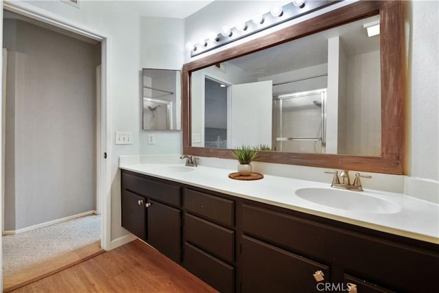 bathroom with hardwood / wood-style flooring, vanity, and a shower with shower door