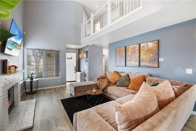 living room featuring a towering ceiling, wood-type flooring, and a fireplace