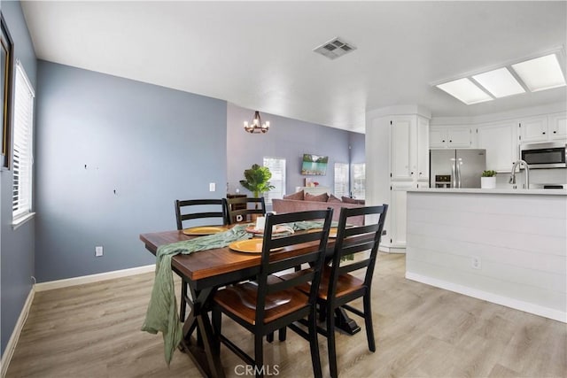 dining room with an inviting chandelier, sink, and light hardwood / wood-style floors