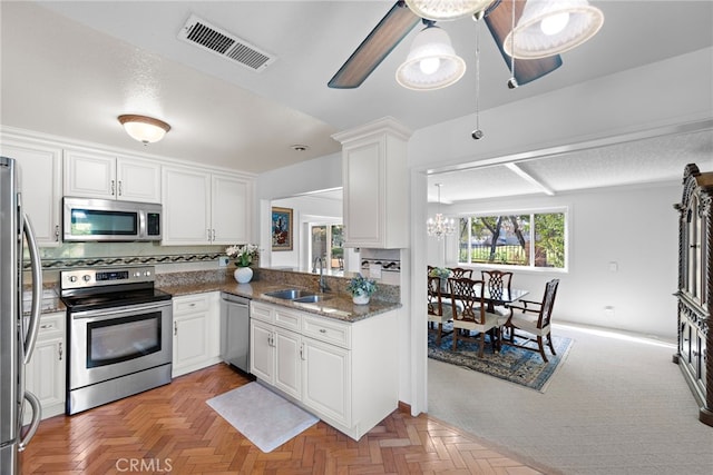 kitchen featuring stainless steel appliances, white cabinetry, a sink, and visible vents