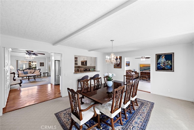 dining area featuring ceiling fan with notable chandelier, beamed ceiling, baseboards, and light colored carpet