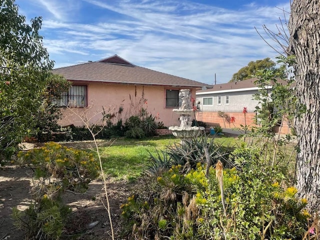 rear view of property featuring a shingled roof and stucco siding