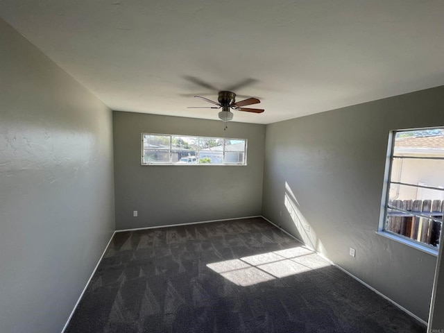 empty room with dark carpet, baseboards, and ceiling fan