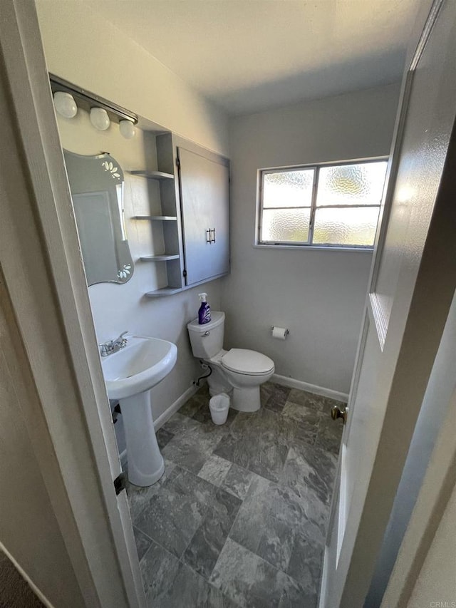 bathroom featuring a sink, toilet, and baseboards