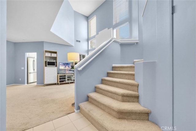 stairway featuring a high ceiling and carpet floors