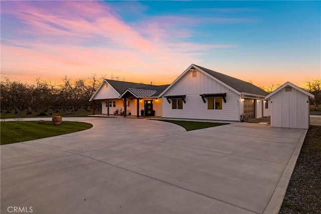 modern farmhouse style home with concrete driveway, board and batten siding, and a lawn