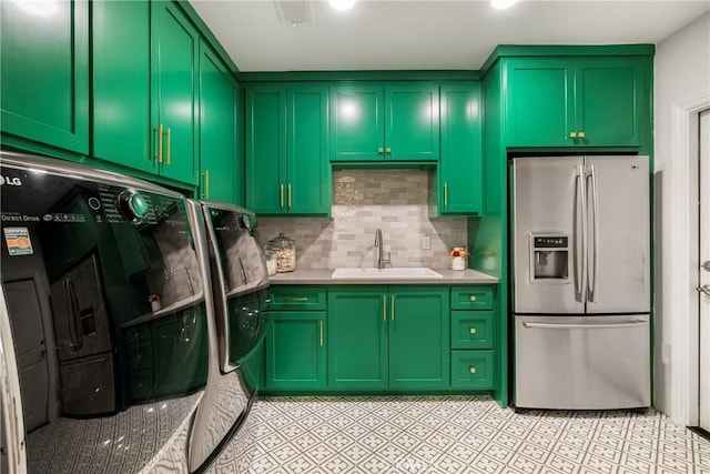 kitchen with a sink, light countertops, tasteful backsplash, stainless steel fridge, and green cabinetry