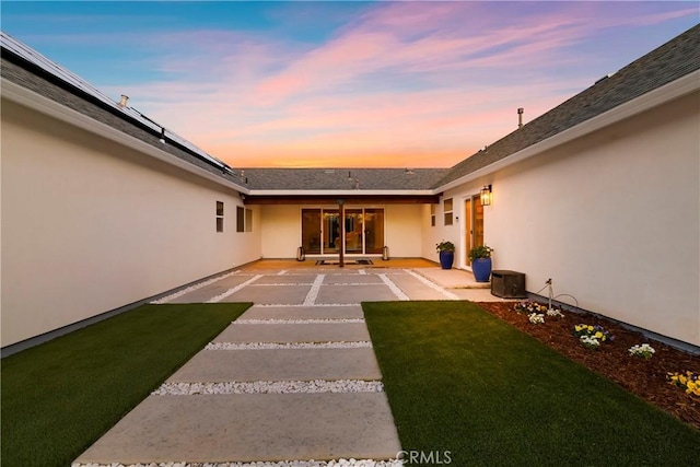 rear view of house featuring a patio area, a lawn, and stucco siding