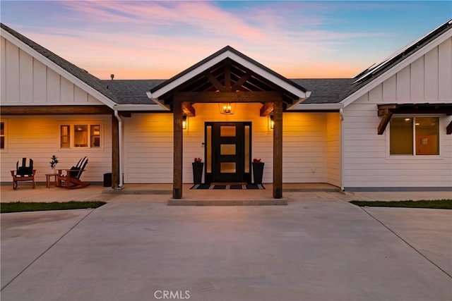 view of front of home featuring a patio area, a shingled roof, and board and batten siding