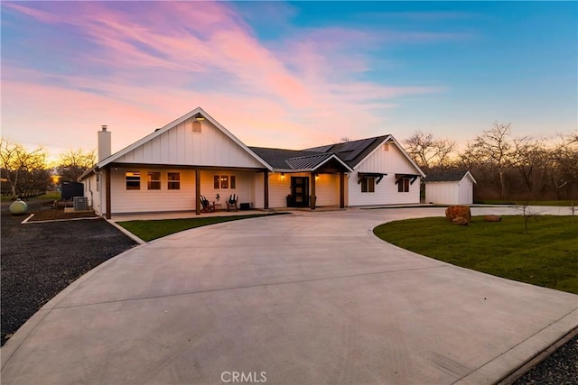 view of front of house with board and batten siding, a front yard, an outdoor structure, and driveway