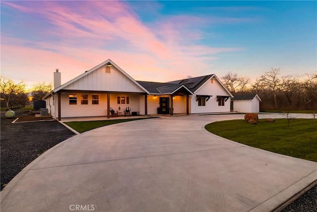 9243 Turner Ln, Durham, CA 95938 - view of front of home with curved driveway, a chimney, a porch, a lawn, and board and batten siding