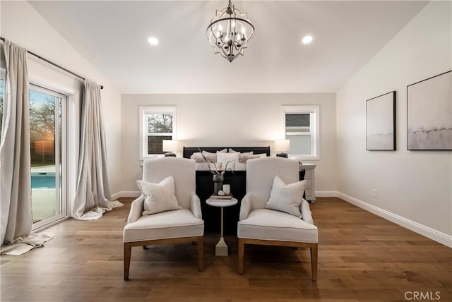 sitting room with lofted ceiling, an inviting chandelier, baseboards, and wood finished floors