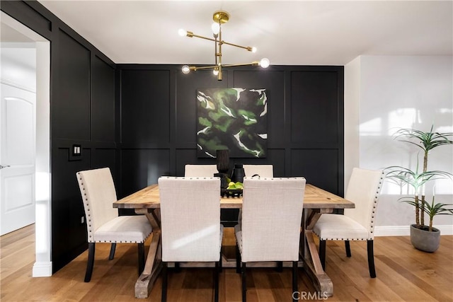 dining room with light wood-style floors, a notable chandelier, and a decorative wall