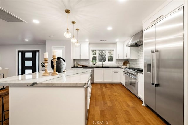 9243 Turner Ln, Durham, CA 95938 - kitchen with high quality appliances, wall chimney exhaust hood, decorative backsplash, a kitchen island, and white cabinets
