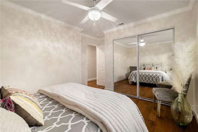 bedroom featuring baseboards, ceiling fan, wood finished floors, crown molding, and a closet