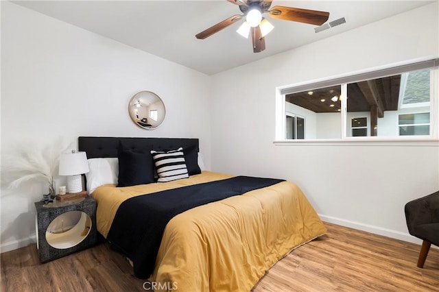 bedroom featuring a ceiling fan, baseboards, visible vents, and wood finished floors