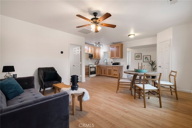 living area featuring light wood-style flooring, visible vents, and a ceiling fan