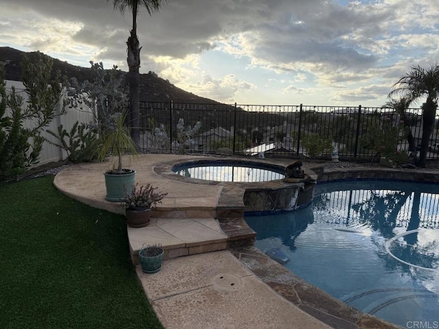 view of swimming pool featuring a mountain view, a patio, and an in ground hot tub