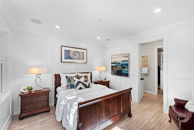 bedroom featuring a decorative wall, crown molding, light wood finished floors, and recessed lighting