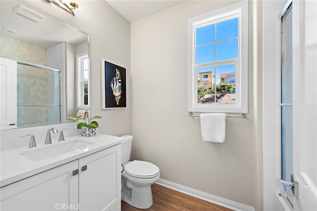 full bathroom featuring toilet, a shower with door, baseboards, visible vents, and wood finished floors