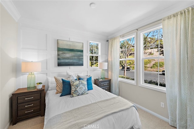 carpeted bedroom with ornamental molding and baseboards