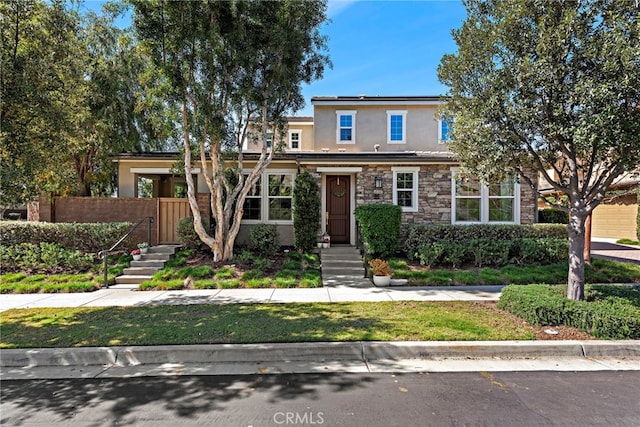 view of front facade featuring stone siding, stucco siding, fence, and roof mounted solar panels